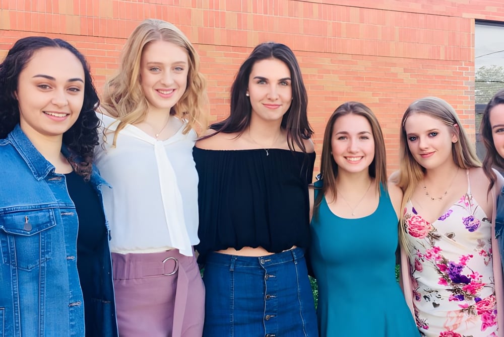 Eine Gruppe von sechs jungen Schülerinnen steht vor einer Backsteinmauer auf dem Gelände der Innisdale Secondary School.
