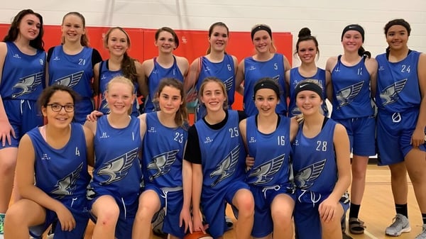 Eine Gruppe von Schülerinnen der Innisdale Secondary School in blauen Uniformen posiert gemeinsam in einer Turnhalle.