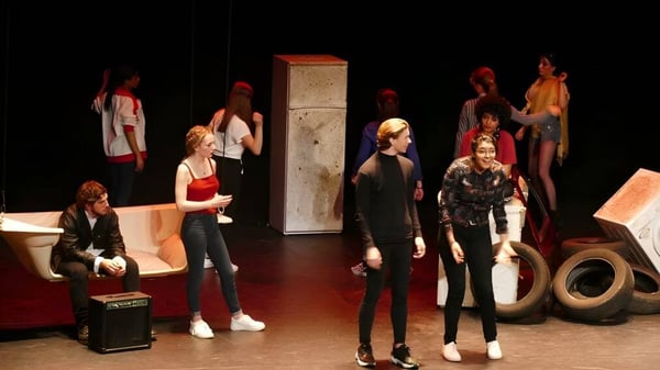 Schüler des Institut Saint-Dominique stehen auf einer Bühne mit Requisiten im Hintergrund.