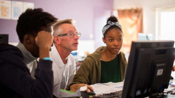 Schüler und ein älterer Mann arbeiten gemeinsam an einem Computer im Institut Saint-Dominique.