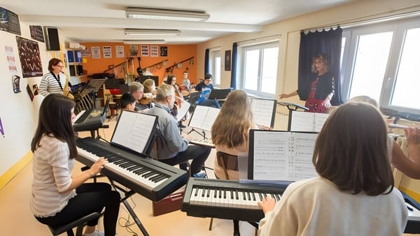 Schüler des Institut Saint-Dominique sind im Musikunterricht, einige spielen Keyboards, andere stehen und hören zu.