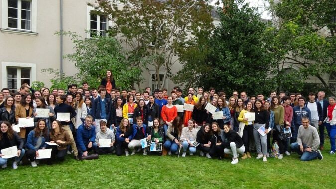 Eine Gruppe junger Menschen versammelt sich auf einer Wiese vor einem Gebäude auf dem Campus der Institution Mongazon.