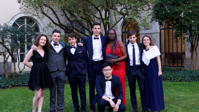 Eine Gruppe von formell gekleideten Personen steht im Garten vor einem Gebäude auf dem Campus der Institution Mongazon.