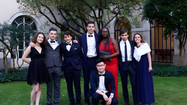 Eine Gruppe von Personen posiert in formeller Kleidung vor einem baumreichen Hintergrund auf dem Gelände der Institution Mongazon.