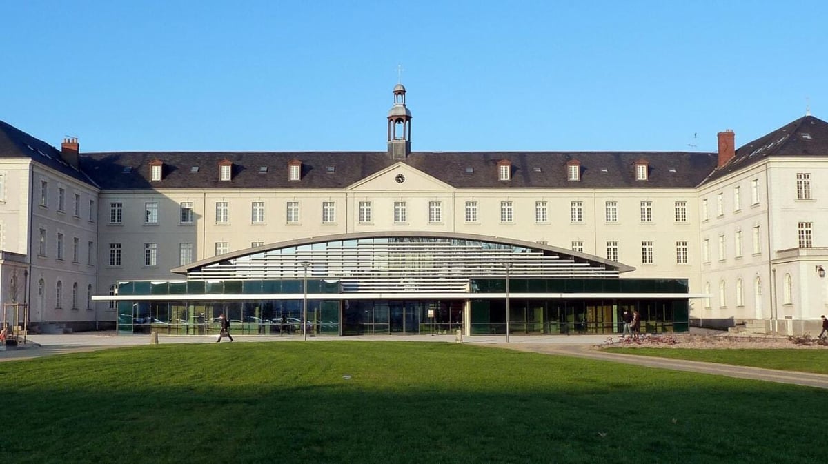 Das historische Gebäude mit großem verglasten Haupteingang auf dem Campus der Institution Mongazon ist von einer gepflegten Rasenfläche umgeben.