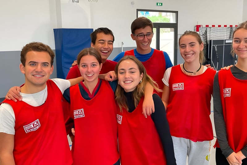 Eine Gruppe von Schülerinnen und Schülern der International Bilingual School of Provence in roten Trikots posiert in der Sporthalle.