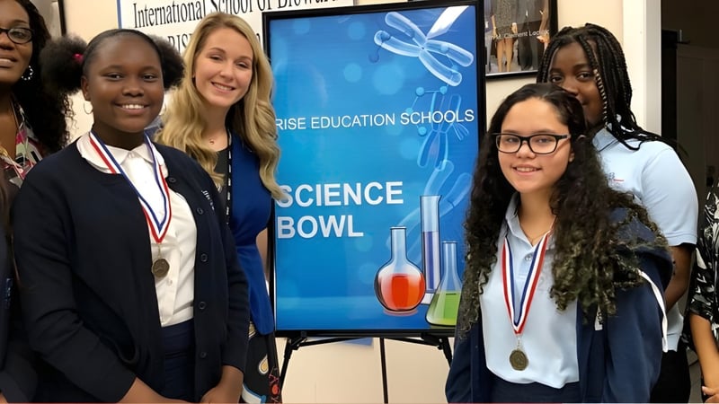 Schüler der International School of Broward stehen mit Medaillen vor dem Banner eines Science Bowl Wettbewerbs.