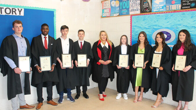 Eine Gruppe von Schülerinnen und Schülern des Inver College steht im Klassenraum in Abschlusskleidung und hält ihre Zertifikate.