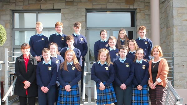 Eine Gruppe Schülerinnen und Schüler in Schuluniformen steht vor einem Steingebäude mit großen Fenstern auf dem Campus des Inver College.
