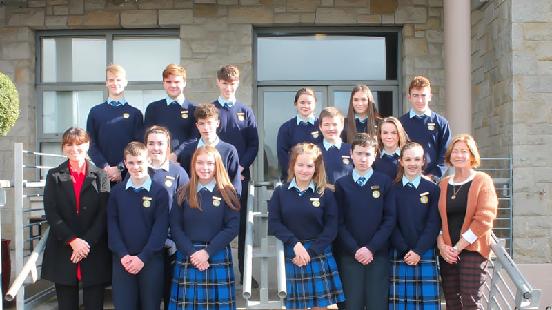 Eine Gruppe Schülerinnen und Schüler in Schuluniformen steht vor einem Steingebäude mit großen Fenstern auf dem Campus des Inver College.