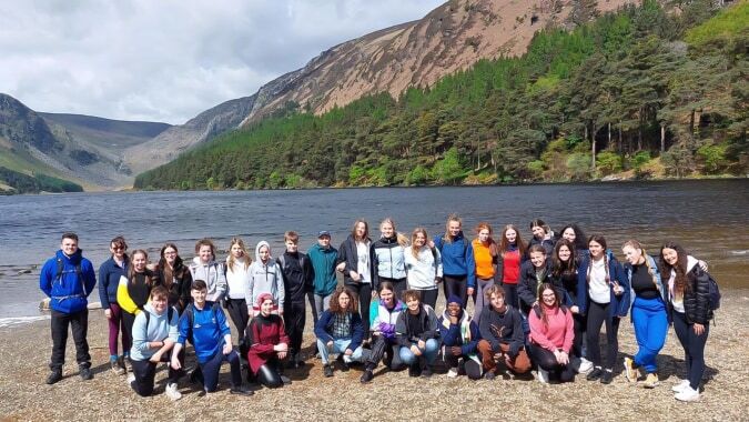 Eine Gruppe von Schülerinnen und Schülern des Inver College steht am Strand vor einer Berglandschaft mit See im Hintergrund.