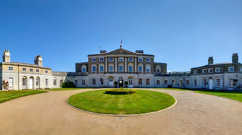 Das prächtige, palaisartige Hauptgebäude der Ipswich High School mit rundem Vorplatz und gepflegtem Rasen unter blauem Himmel.