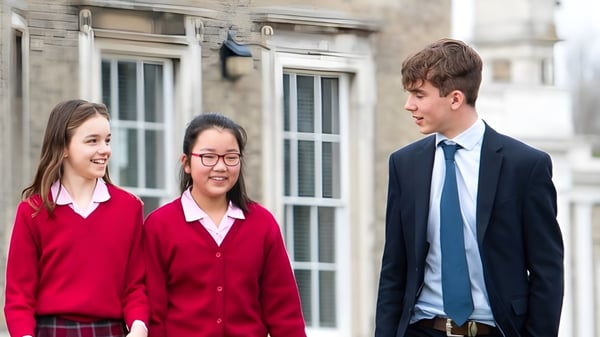 Drei Schüler der Ipswich High School stehen vor einem Gebäude mit großen Fenstern und unterhalten sich.
