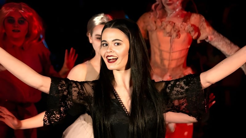 Eine Schülerin der Ipswich High School führt eine Tanzperformance in schwarzem Spitzenkleid vor einer Gruppe in roten Kostümen auf.