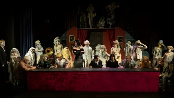 Eine große Gruppe von Schülerinnen und Schülern auf der Bühne der Ipswich School vor rotem Vorhang und dekoriertem Hintergrund.