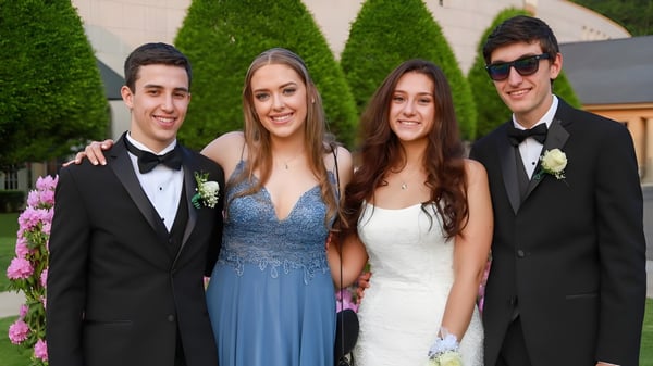 Vier gut gekleidete Personen posieren gemeinsam vor grüner Kulisse auf dem Gelände der Ipswich School.