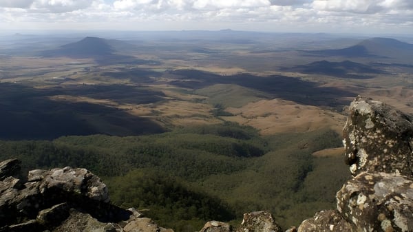 Eine bergige Landschaft mit bewaldeten Tälern und Gipfeln in der Ferne nahe der Ipswich State High School.