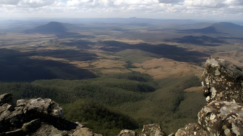 Eine bergige Landschaft mit bewaldeten Tälern und Gipfeln in der Ferne nahe der Ipswich State High School.