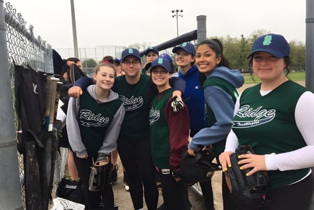 Eine Gruppe Schüler der Iroquois Ridge High School posiert gemeinsam vor einem umzäunten Sportfeld.