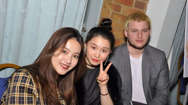 Drei Schülerinnen und Schüler der International School of Creative Arts posieren gemeinsam vor einer Backsteinwand im Wohnbereich.