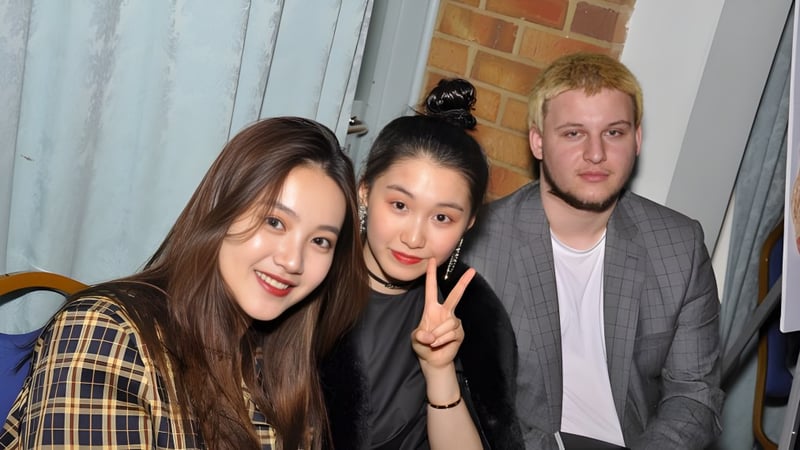 Drei Schülerinnen und Schüler der International School of Creative Arts posieren gemeinsam vor einer Backsteinwand im Wohnbereich.