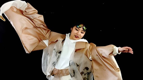 Eine Person in beige Kostüm führt eine Tanzperformance auf der Bühne der International School of Creative Arts (ISCA) auf.