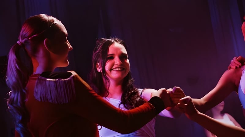 Zwei Schülerinnen tanzen zusammen auf der Bühne des Itchen Sixth Form College unter farbiger Bühnenbeleuchtung.