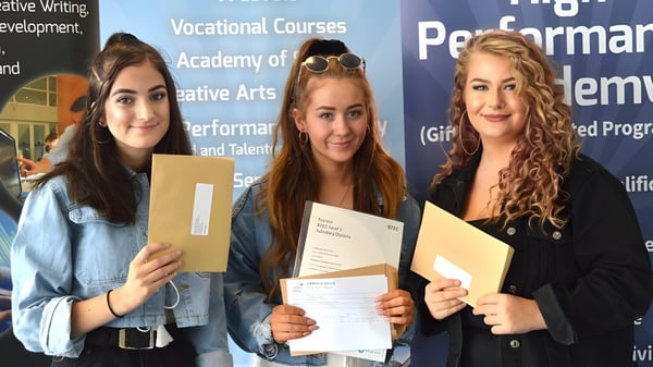 Drei Schülerinnen halten vor einem Informationshintergrund zum Itchen Sixth Form College ihre Urkunden.