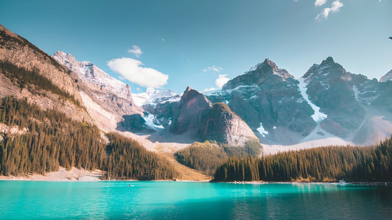 Ein alpiner See mit verschneiten Bergen und einem Wald im Vordergrund nahe der James Fowler High School.