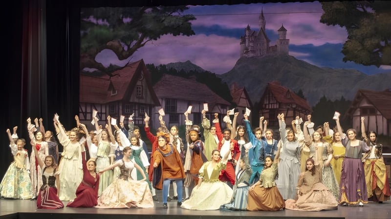 Schüler der James M. Hill Memorial High School stehen vor einer mittelalterlichen Burg- und Dorfszene.