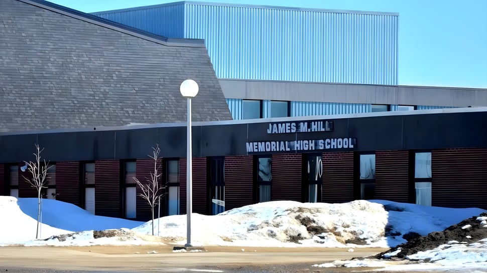 Das große Gebäude der James M. Hill Memorial High School steht auf schneebedecktem Gelände.