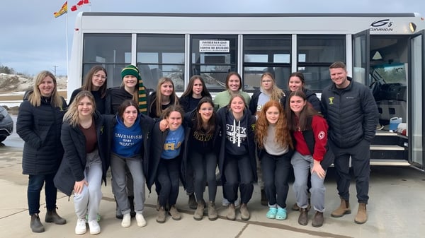 Eine Gruppe von Schülerinnen und Schülern steht vor dem Gebäude der James M. Hill Memorial High School.