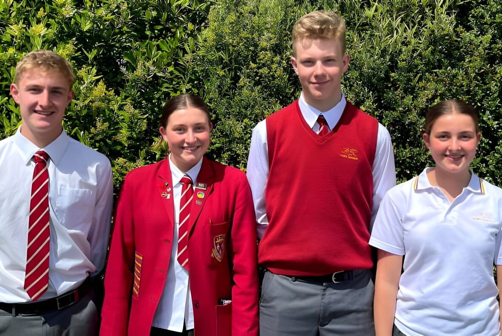 Vier Schülerinnen und Schüler stehen auf einer grünen Wiese auf dem Campus des James Hargest College.