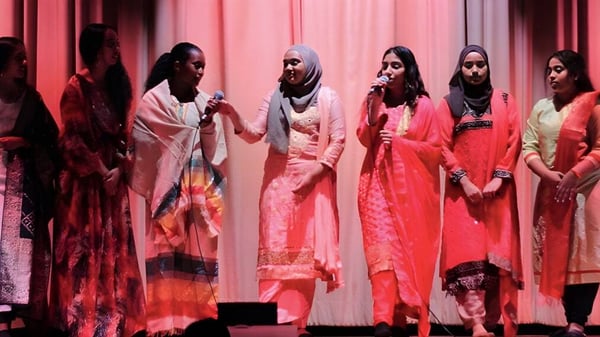 Eine Gruppe von Schülerinnen in bunten traditionellen Kleidern steht auf der Bühne des Jarvis Collegiate Institute.