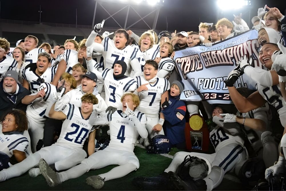 Eine Gruppe von Football-Spielern feiert auf dem Spielfeld bei Nacht auf dem Campus der Jeffco Public Schools.