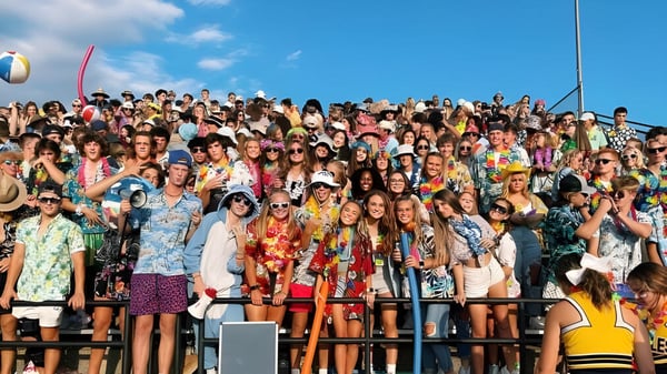 Eine große Gruppe von Menschen versammelt sich draußen unter dem klaren Himmel auf dem Gelände der Jenison High School.