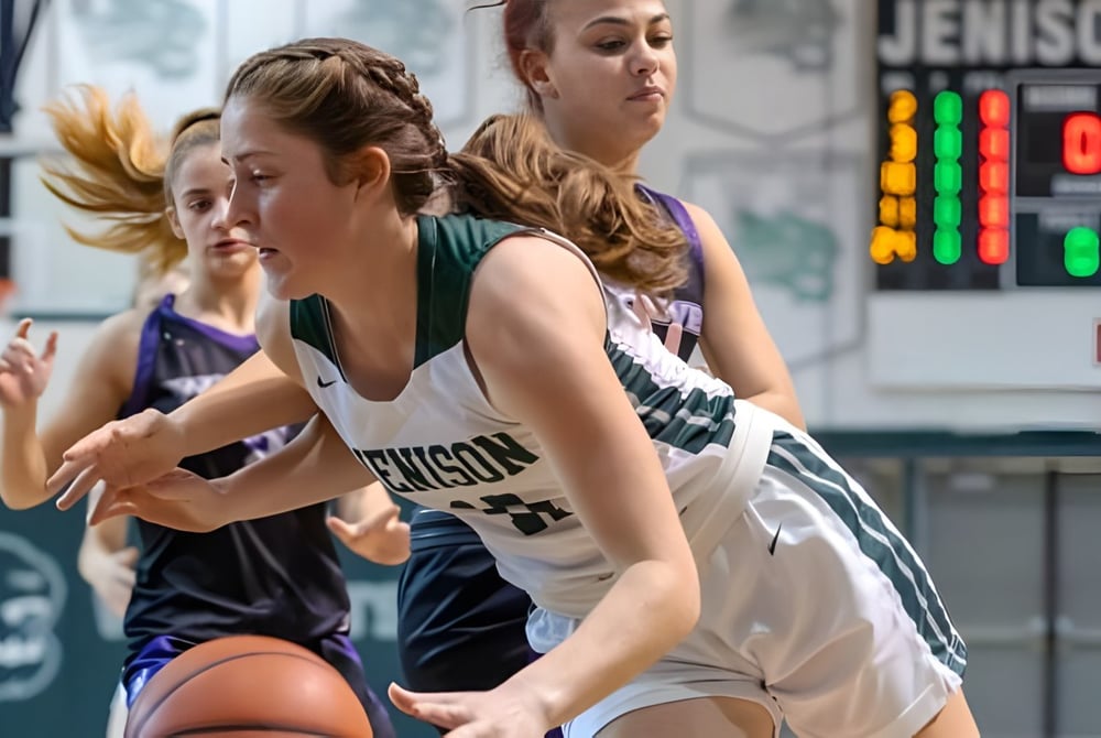 Zwei Basketballspielerinnen kämpfen um den Ball auf dem Spielfeld bei Jenison Public Schools.