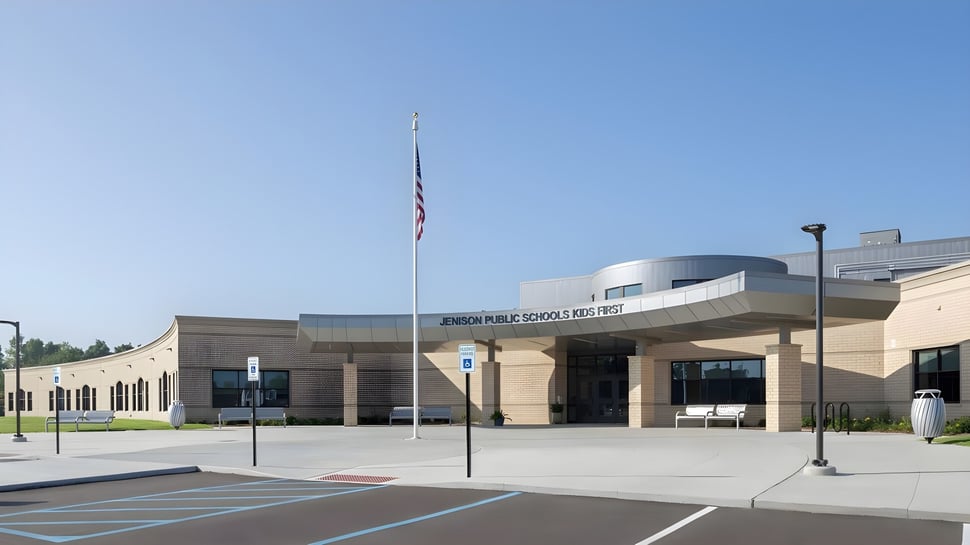 Das moderne Gebäude mit geschwungenem Dach und amerikanischer Flagge vor der Jenison Public Schools.