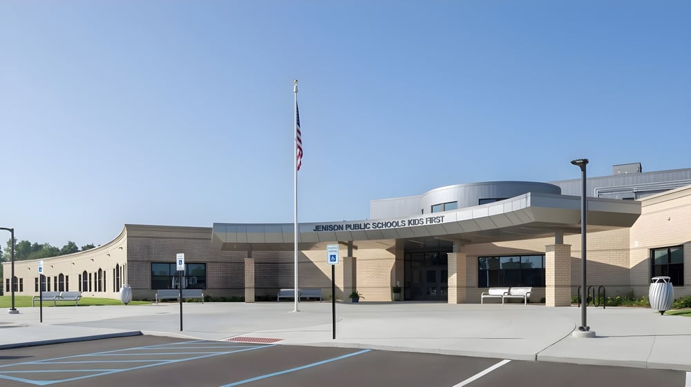 Das moderne Gebäude mit geschwungenem Dach und amerikanischer Flagge vor der Jenison Public Schools.