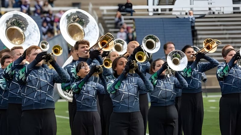 Die Marching Band der Jenison Public Schools tritt auf einem Spielfeld vor Zuschauern auf.