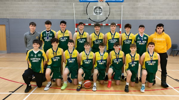 Eine Gruppe von Schülern der Jesus and Mary Secondary School posiert in der Turnhalle vor einem Basketballkorb.