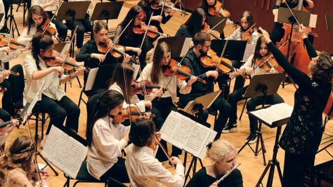 Das Orchester der Jesus and Mary Secondary School führt ein Konzert mit Streichinstrumenten auf der Bühne auf.