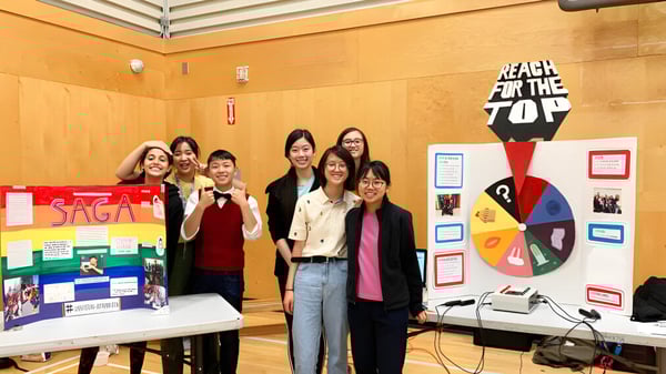 Eine Gruppe von Schülerinnen steht vor einem Anschlagbrett auf dem Campus der J.N. Burnett Secondary School.