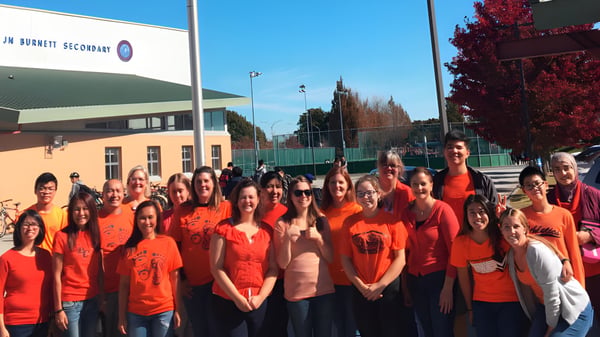 Eine Gruppe von Schülern der J.N. Burnett Secondary School steht vor einem Gebäude mit roten Shirts.