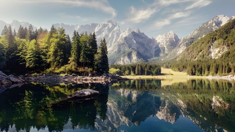 Der alpine See mit schneebedeckten Bergen und Nadelwäldern spiegelt die Landschaft am John Abbott College wider.