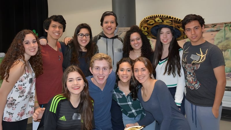 Eine Gruppe Schülerinnen und Schüler posiert zusammen in einem Raum auf dem Campus des John Abbott College.