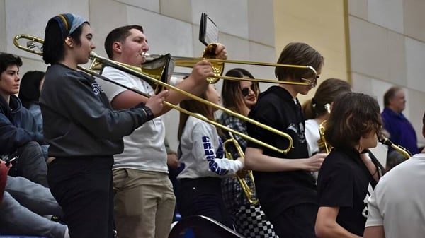Eine Gruppe von Schülern der John Bapst Memorial High School versammelt sich mit Musikinstrumenten im Flur.