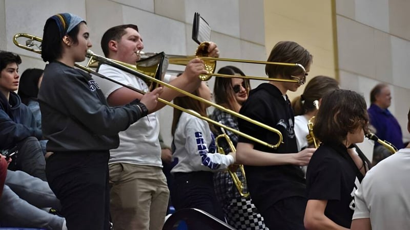 Eine Gruppe von Schülern der John Bapst Memorial High School versammelt sich mit Musikinstrumenten im Flur.