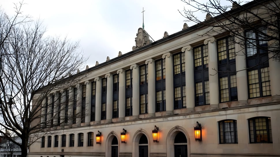 Das prächtige Gebäude mit Bogenfenstern auf dem Gelände der John Bapst Memorial High School ist von kahlen Bäumen umgeben.