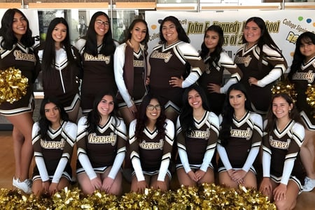 Eine Gruppe Schülerinnen der John F. Kennedy High School posiert mit Pompons in der Turnhalle.